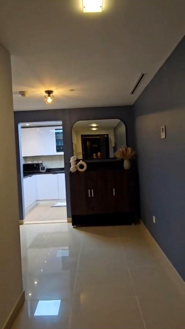 Clean apartment hallway with polished floor tiles leading to the kitchen