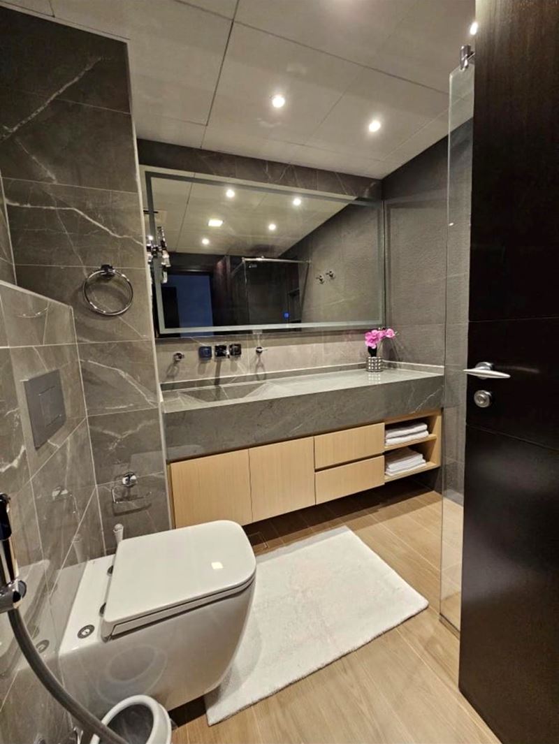Finished bathroom with grey marble-effect tiles, stone vanity and illuminated mirror