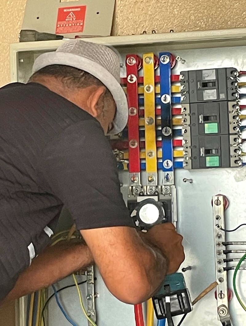 Tafirud electrician working on a distribution board with colour-coded busbars and circuit breakers