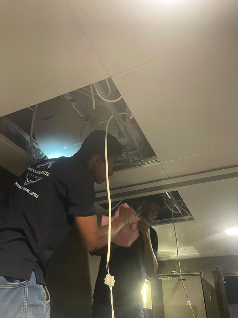 Tafirud technician inspecting services above an open ceiling during maintenance