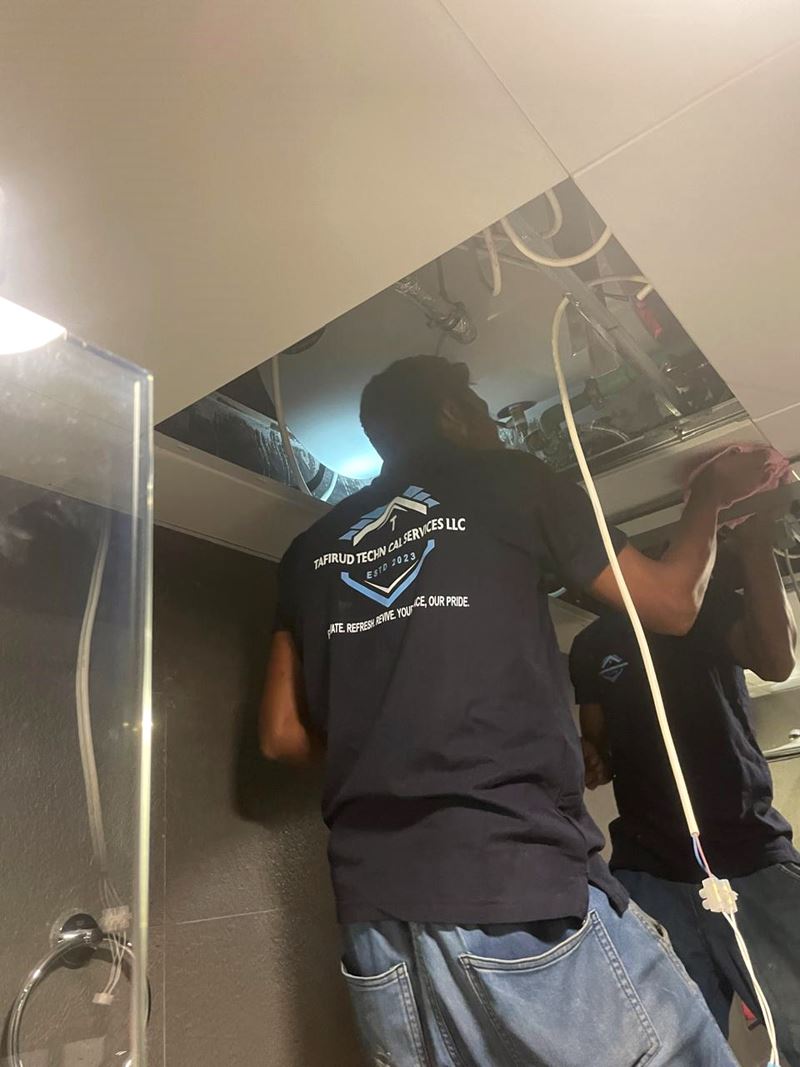 Tafirud technician in the company’s navy uniform working on services above a ceiling
